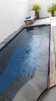 a swimming pool with a bench next to a building at Villa Olivia in Seminyak