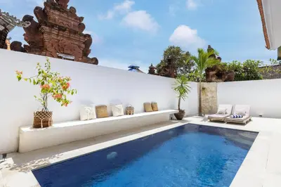 a swimming pool in a backyard with a white wall at Villa Canggu Beach Coconut - walking distance to Beach & Bars! in Canggu