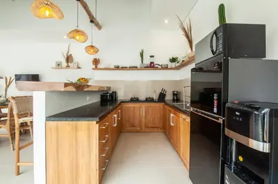 a kitchen with wooden cabinets and black appliances at Simple & Magical Villas VILLA SAMBALI in Seminyak
