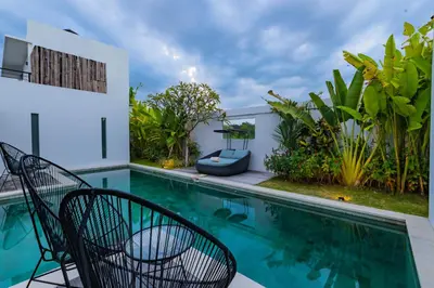 a swimming pool with chairs next to a house at Hedonia Luxury Villas in Seminyak