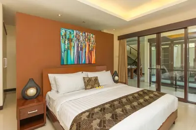 a bedroom with a bed and a painting on the wall at Villa Cascade in Seminyak