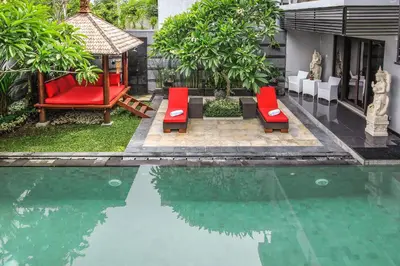 a pool with two red chairs and a swing at Villa Cascade in Seminyak