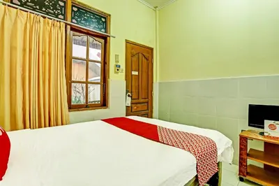 a bedroom with a bed and a window and a television at OYO Collection O 91125 Puri Dewa Bharata in Jimbaran