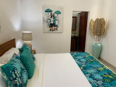 a bedroom with a bed with green and blue pillows at Villa Tenang Legian in Legian