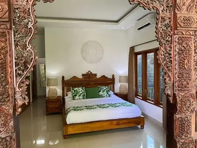 a bedroom with a bed with green and white pillows at Villa Tenang Legian in Legian
