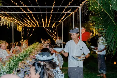 a man holding a plate of food in front of a table at Istana Semer - Balinese Style Private Event Villa, with Large Pool, Gardens and Cook - Near to Canggu & Seminyak in Kerobokan
