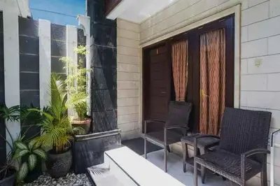 a porch with two chairs and a wooden door at DENAYS GUESTHOUSE JIMBARAN in Jimbaran
