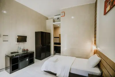 a hotel room with a bed and a television at DENAYS GUESTHOUSE JIMBARAN in Jimbaran