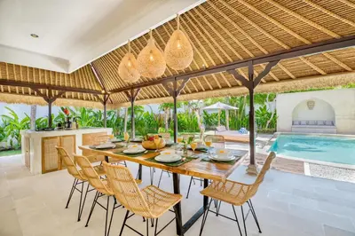 an outdoor dining area with a table and chairs and a swimming pool at Villa Chandika - 4 BDR Villa with private Pool, walk to the beach in Seminyak