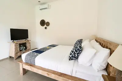 a bedroom with a bed with white sheets and a television at CASA BEGJA I Tranquil 2BR Villa w Private Pool in Mertanadi in Seminyak