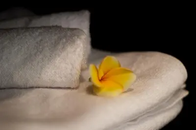 a person holding a yellow flower on a towel at CASA BEGJA I Tranquil 2BR Villa w Private Pool in Mertanadi in Seminyak