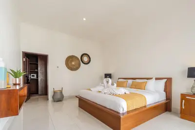 a bedroom with a bed and a clock on the wall at Casa Jinah 1 I Simply Modern Twin Villas (2BR) with Private Pool in Seminyak