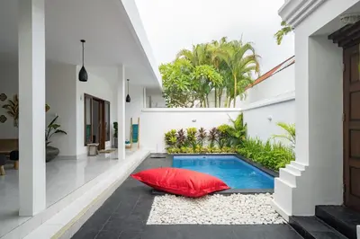 a courtyard with a swimming pool and a red pillow at Casa Jinah 1 I Simply Modern Twin Villas (2BR) with Private Pool in Seminyak