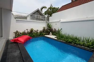 a swimming pool with a red pillow next to a building at Casa Jinah 2 I Simply Modern Twin Villas (2BR) in Bidadari in Seminyak