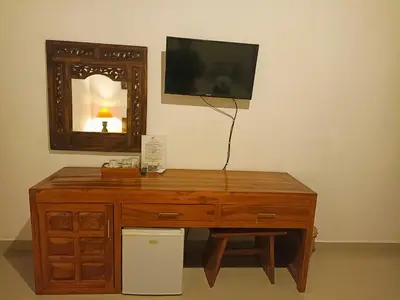 a wooden desk with a television and a mirror at Kusnadi Hotel in Legian