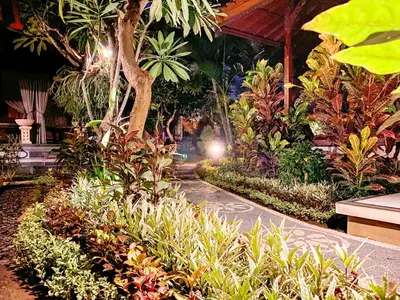 a walkway in a garden with plants and trees at Kusnadi Hotel in Legian