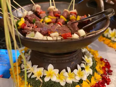 a bowl of meat and vegetables on top of a cake at Kusnadi Hotel in Legian