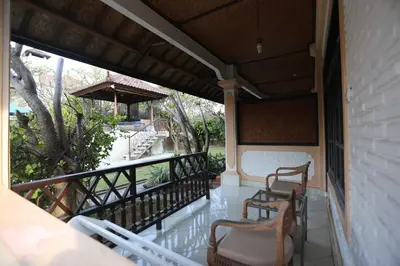 a porch with two chairs and a table at Fat Yogi Cottages in Kuta