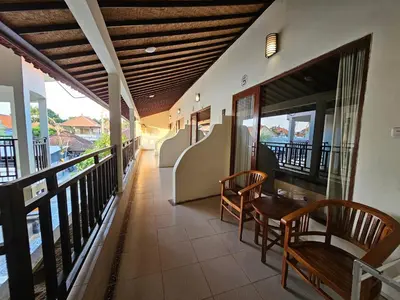 a balcony with two chairs and a table at Tegalsari Guest House Canggu in Canggu