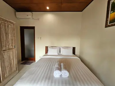 a bedroom with a bed with two slippers on it at Tegalsari Guest House Canggu in Canggu