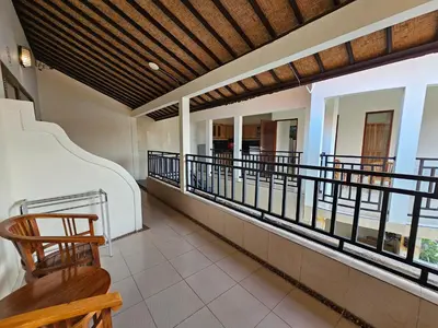 a room with a balcony with chairs and windows at Tegalsari Guest House Canggu in Canggu