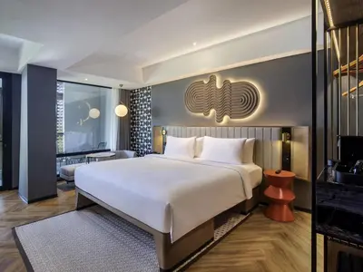 a bedroom with a large bed and a living room at Tribe Bali Kuta Beach in Kuta