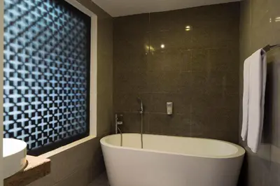 a bathroom with a tub and a sink and a toilet at Natya Hotel Kuta in Kuta