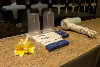 a counter with two test tubes and a flower on it at Natya Hotel Kuta in Kuta