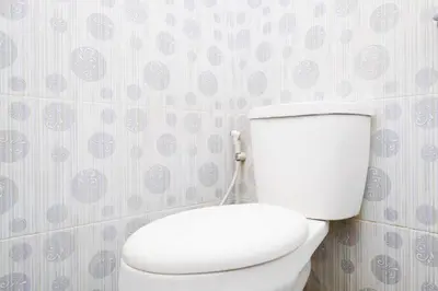 a white toilet in a bathroom with purple wallpaper at RedDoorz at Serenity Inn Teuku Umar Denpasar in Denpasar