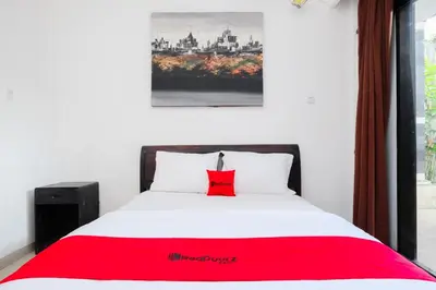 a bedroom with a red pillow on a bed at RedDoorz at Serenity Inn Teuku Umar Denpasar in Denpasar