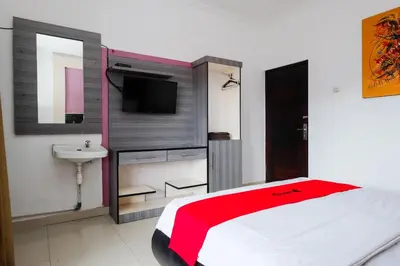 a bedroom with a bed and a sink and a tv at RedDoorz at Serenity Inn Teuku Umar Denpasar in Denpasar