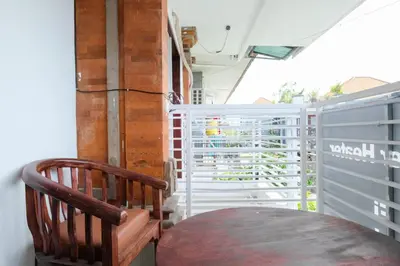 a balcony with a wooden chair and a table at RedDoorz at Serenity Inn Teuku Umar Denpasar in Denpasar