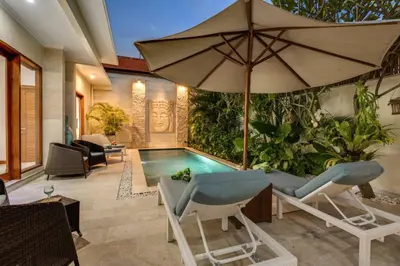 an indoor pool with chairs and an umbrella at Central Seminyak, 3BR, Ensuites, Sleep 6, Peaceful in Seminyak