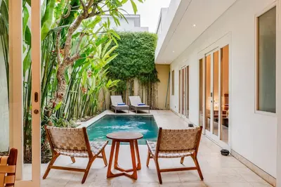 a patio with a pool and two chairs and a table at Villa Vana, Sitara Villa Group in Seminyak