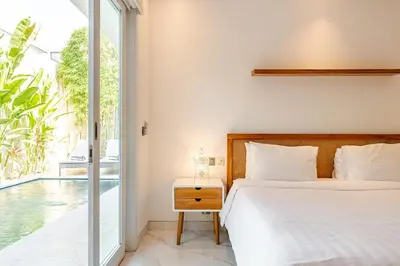 a bedroom with a bed and a view of a pool at Villa Vana, Sitara Villa Group in Seminyak