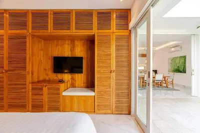 a bedroom with a wooden wall with a television in it at Villa Vana, Sitara Villa Group in Seminyak