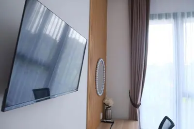 a flat screen tv hanging on a wall next to a window at Olivia SOHO Guest House in Legian