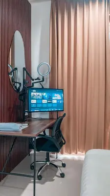 a desk with a computer and a chair and a mirror at Olivia SOHO Guest House in Legian