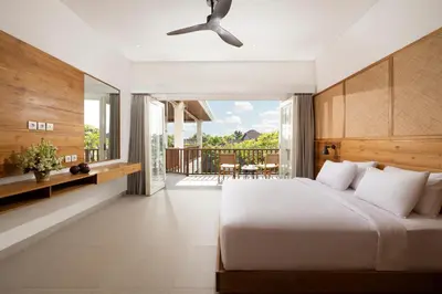 a bedroom with a large bed and a balcony at Villa Christie By Nakula in Seminyak
