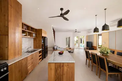 a kitchen with wooden cabinets and a ceiling fan at Villa Christie By Nakula in Seminyak
