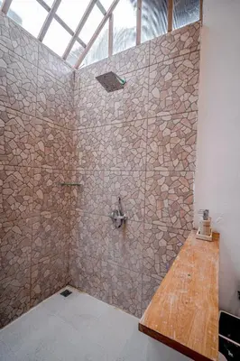 a bathroom with a shower with a stone wall at Villa Deba 3 by Bali Villa Solutions in Seminyak