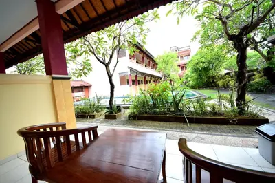 a wooden table and chairs on a patio with trees at Celebbest in Kuta