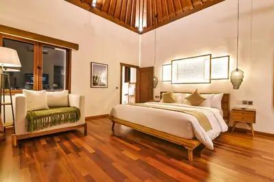 a bedroom with a large bed and a chair at Villa Kalita Bali in Seminyak
