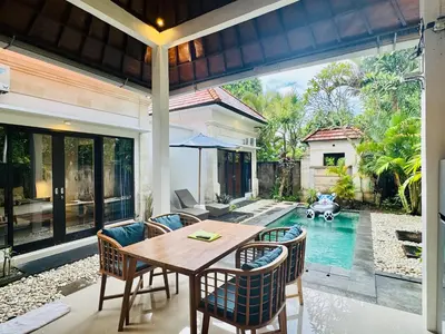 a dining room with a table and chairs and a pool at Villa Banua Seminyak in Seminyak
