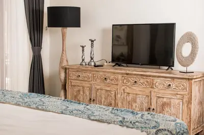 a bedroom with a tv on a wooden dresser at Relax Bali Villas in Legian