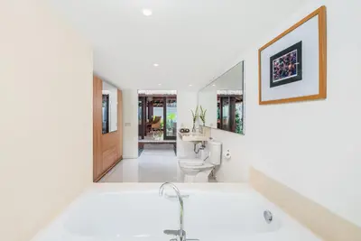 a white bathroom with a tub and a toilet at Kundalini Residence in Seminyak