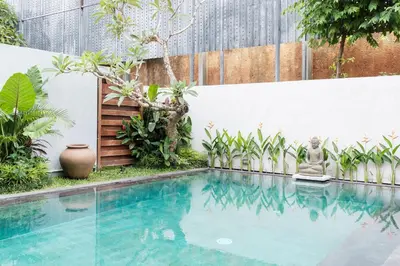 a swimming pool in the middle of a garden at Kundalini Residence in Seminyak