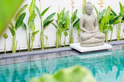a statue sitting next to a swimming pool at Kundalini Residence in Seminyak