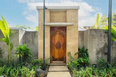 a wooden door on a house with a concrete wall at Kundalini Residence in Seminyak