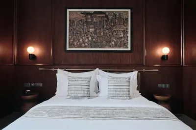 a bed with white sheets and pillows in a room at Munno Villa in Canggu